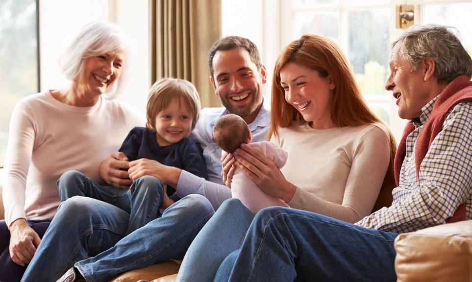 Familie, mit Neugeborenem, sitzt mit den Grosseltern auf dem Sofa