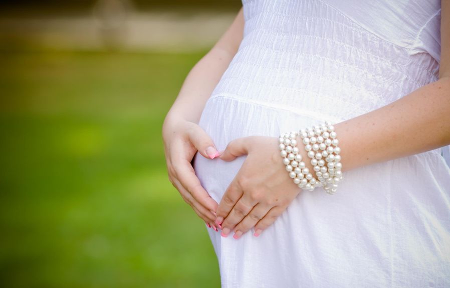 Schwangere festlich gekleidet, mit Perlenarmband
