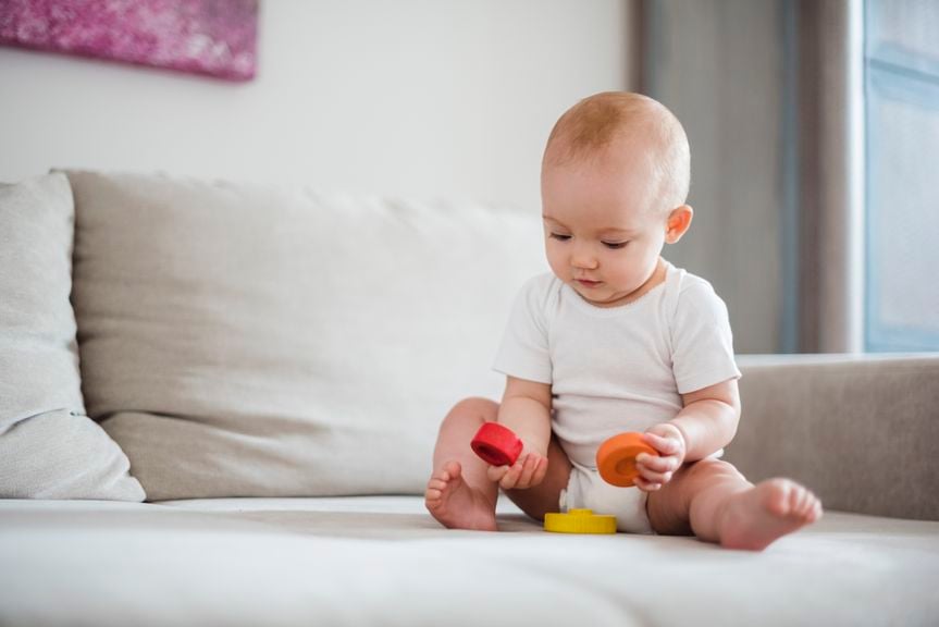 Baby sitzt auf dem Sofa und spielt