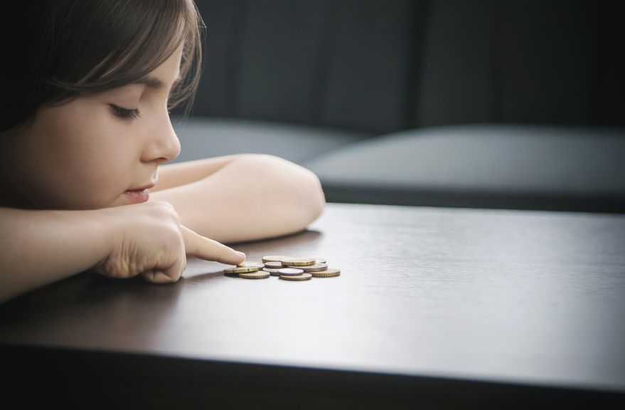 Ernst blickendes Kind zählt Münzen