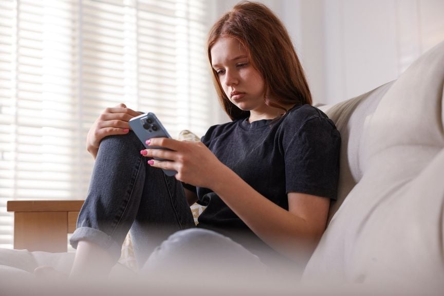 Trauriger weiblicher Teenager schaut aufs Handy