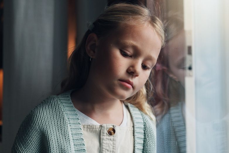 Mädchen lehnt den Kopf an das Fenster