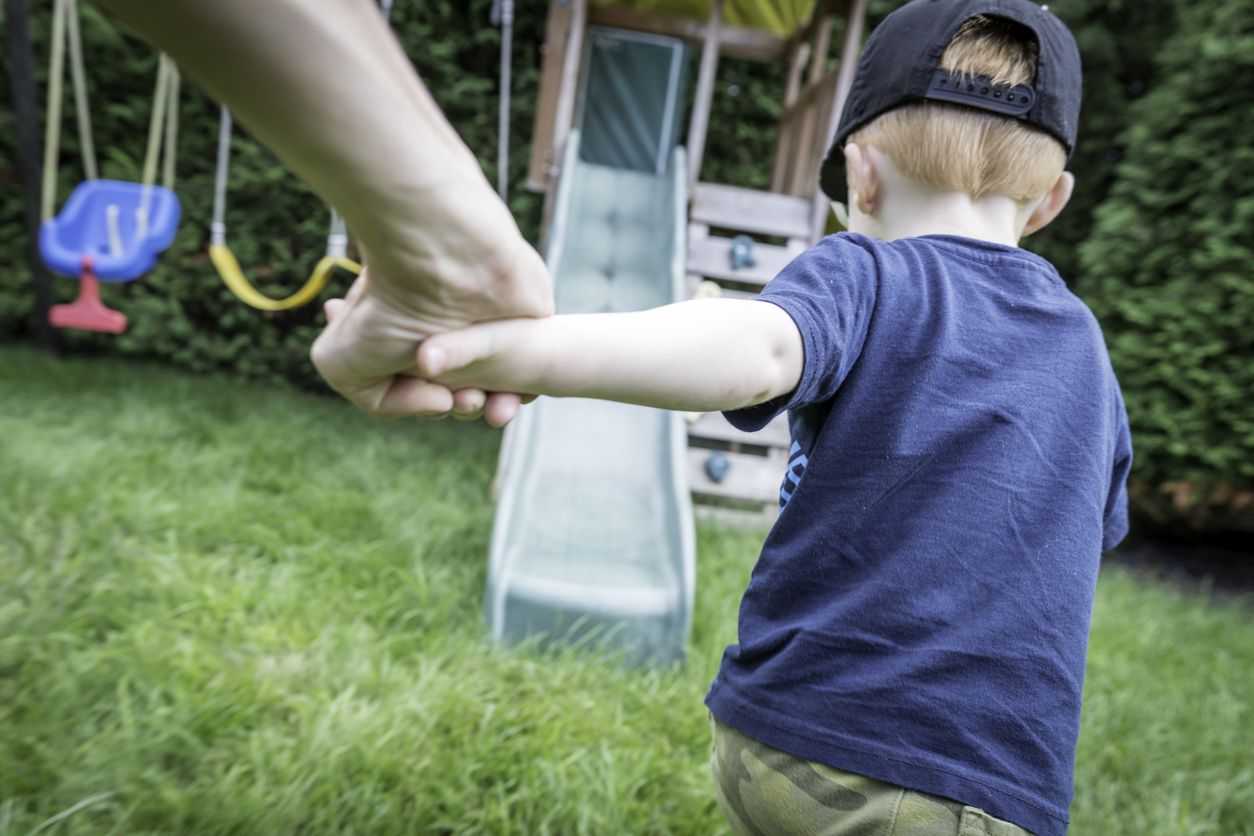 Kind rennt mit Erwachsenem auf den Spielplatz 