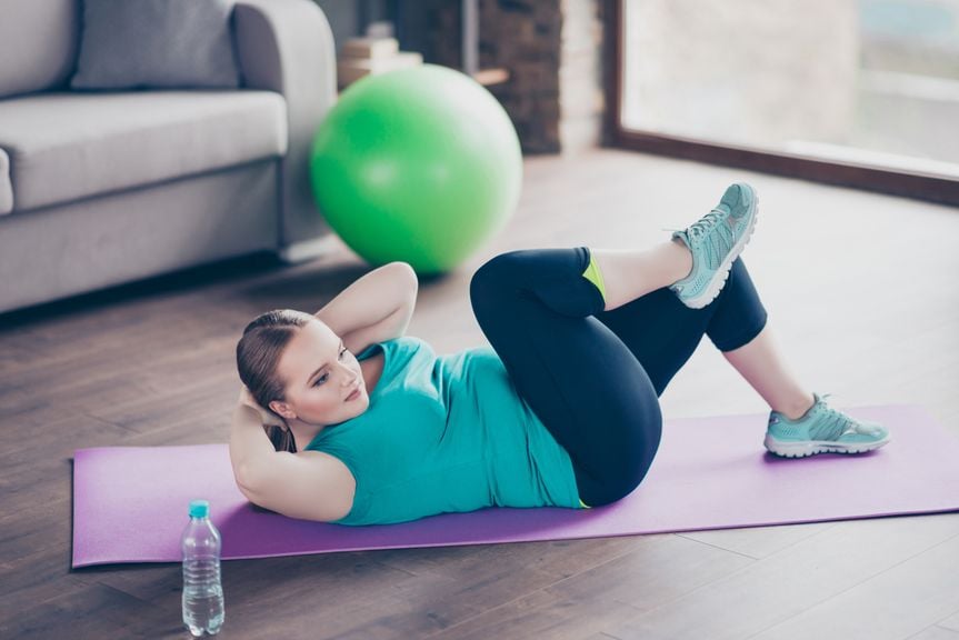 Frau zu Hause auf einer Yogamatte macht Beckenboden- und Bauchmuskelübungen 