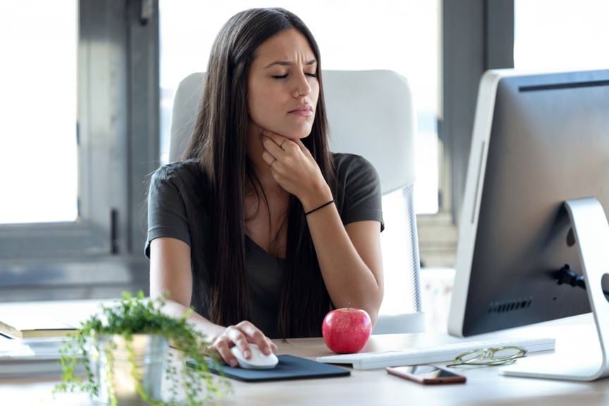 Frau am Arbeitsplatz, Hand am Hals