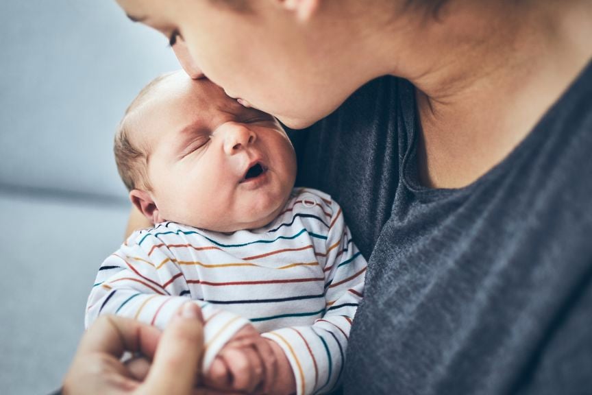 Mutter küsst Baby auf die Stirn