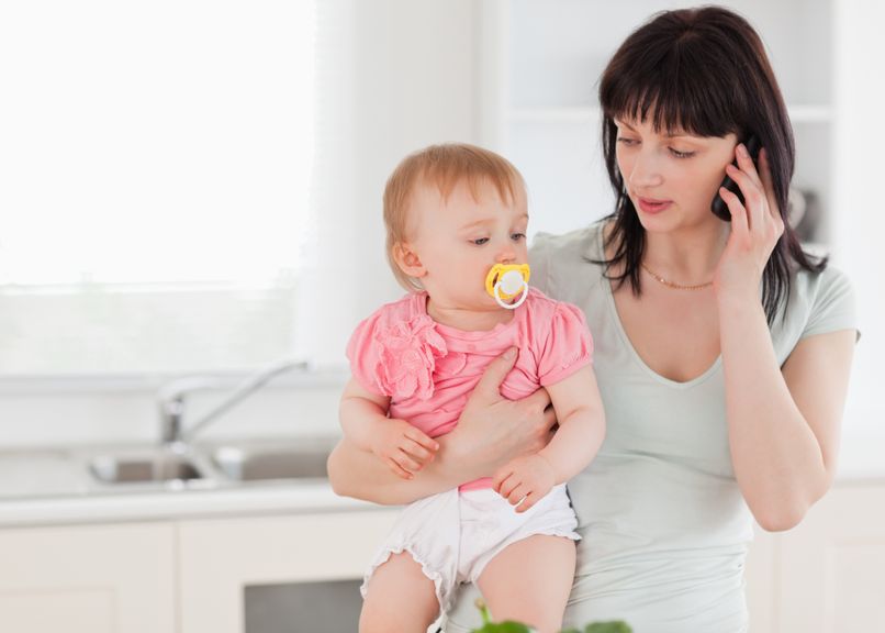 Mutter mit Baby im Arm telefoniert
