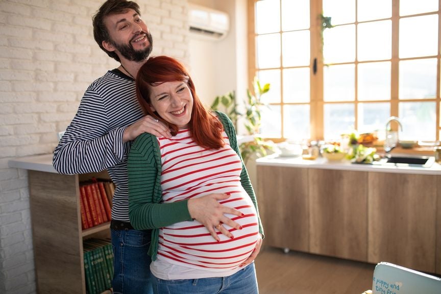 Mann massiert seiner hochschwangeren Frau die Schultern
