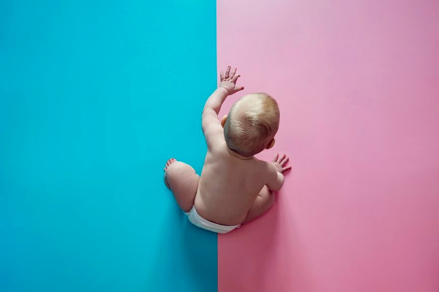 Baby sitzt auf rosa-blauem Boden