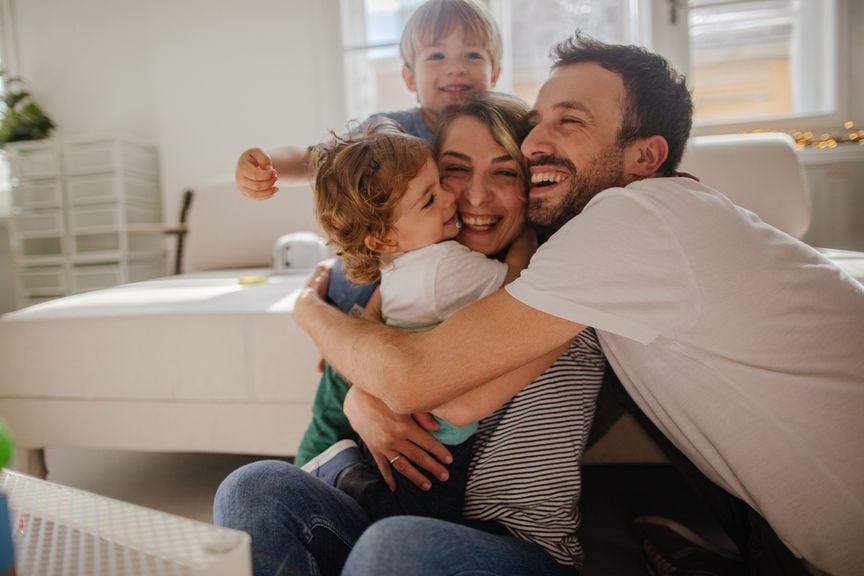 Vierköpfige Familie umarmt sich lachend