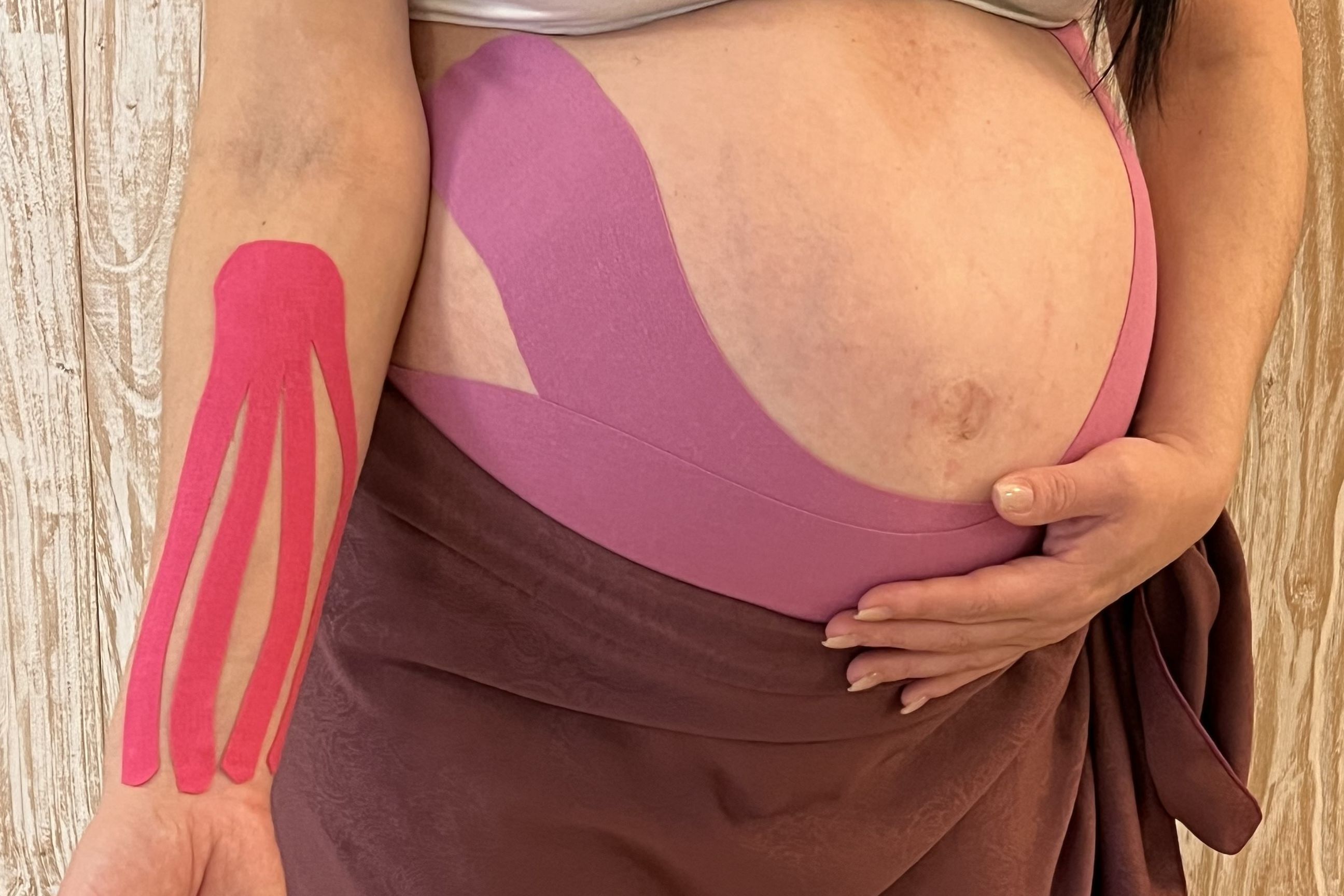 Schwangere mit Kinesio-Tapes an Arm und Bauch
