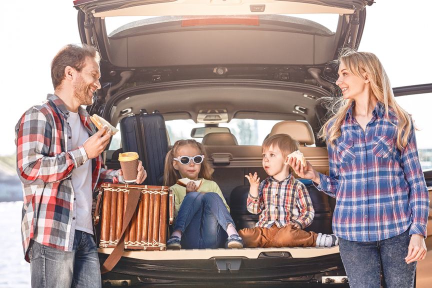 Familie mit zwei Kindern macht eine Essenspause auf einer Autoreise