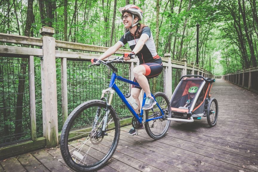 Frau mit Veloanhänger und Baby unterwegs