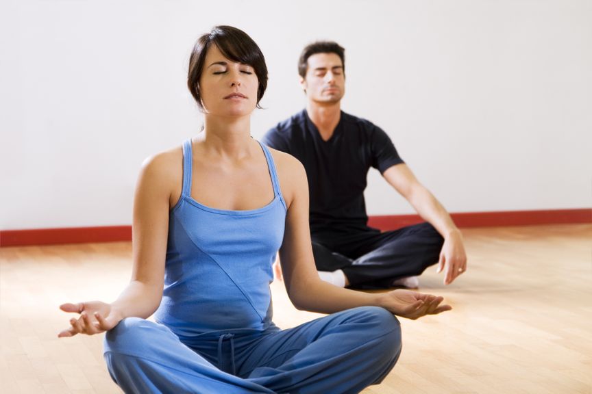 Paar am Boden im Schneidersitz und macht Yoga-Übungen