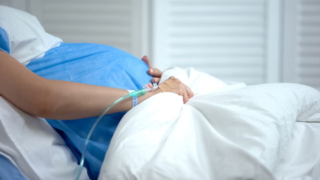 Schwangere liegt in einem Spitalbett mit einer Infusion 