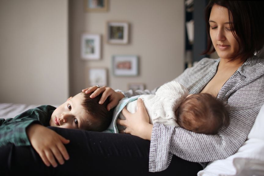 Mutter mit zwei Kindern stillt das Baby