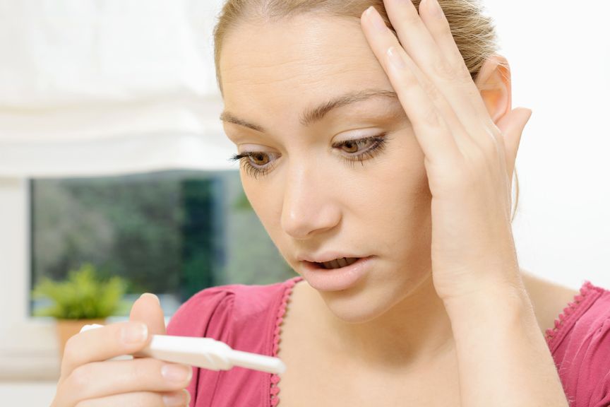 Frau schaut entsetzt und erstaunt auf den Schwangerschaftstest                                        
