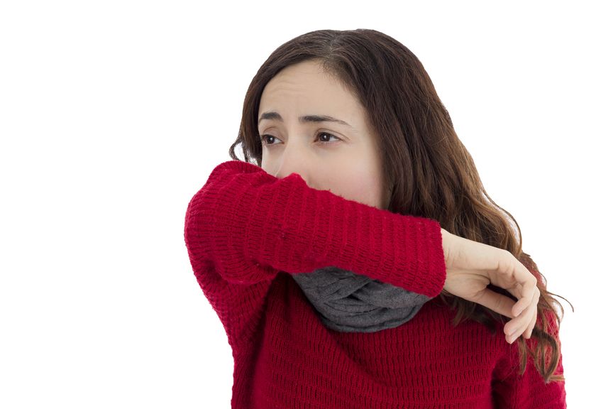 Erkältete Frau niest in die Armbeuge