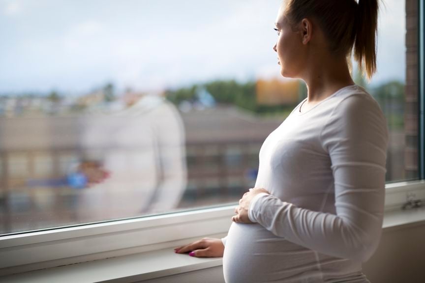 Schwangere schaut aus dem Fenster