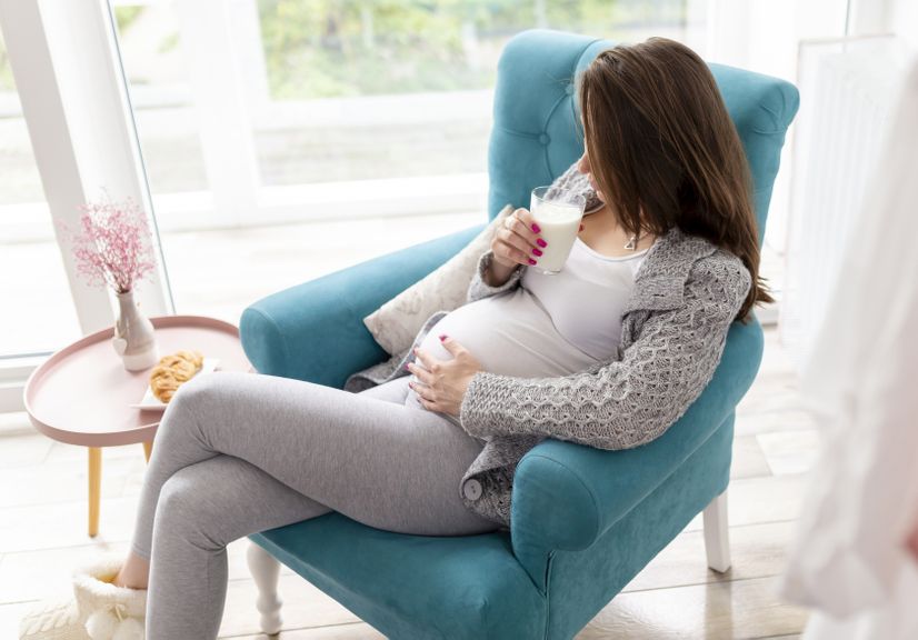 Schwangere im Sessel trinkt Milch