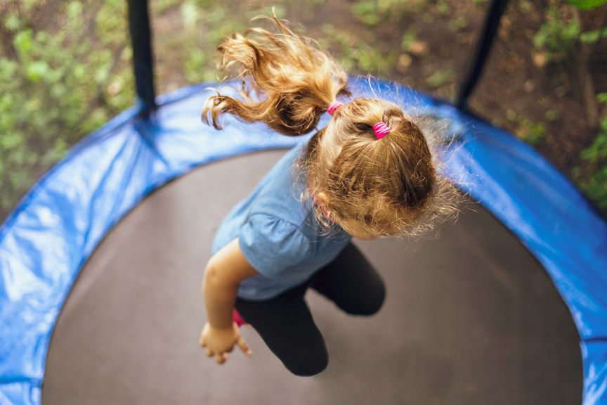 Obenansicht eines Kindes mit Pferdeschwanz, das auf einem Trampolin springt