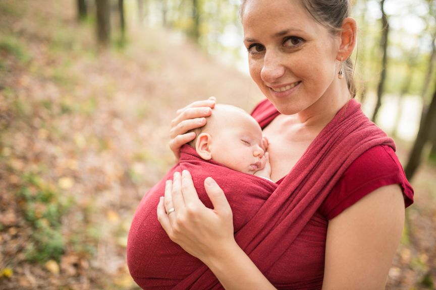 Mutter trägt ihr Baby im Tragetuch im Wald