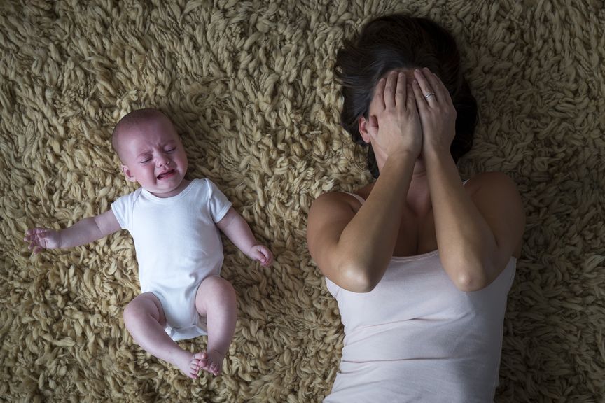 Mutter und weinendes Baby liegen auf dem Boden