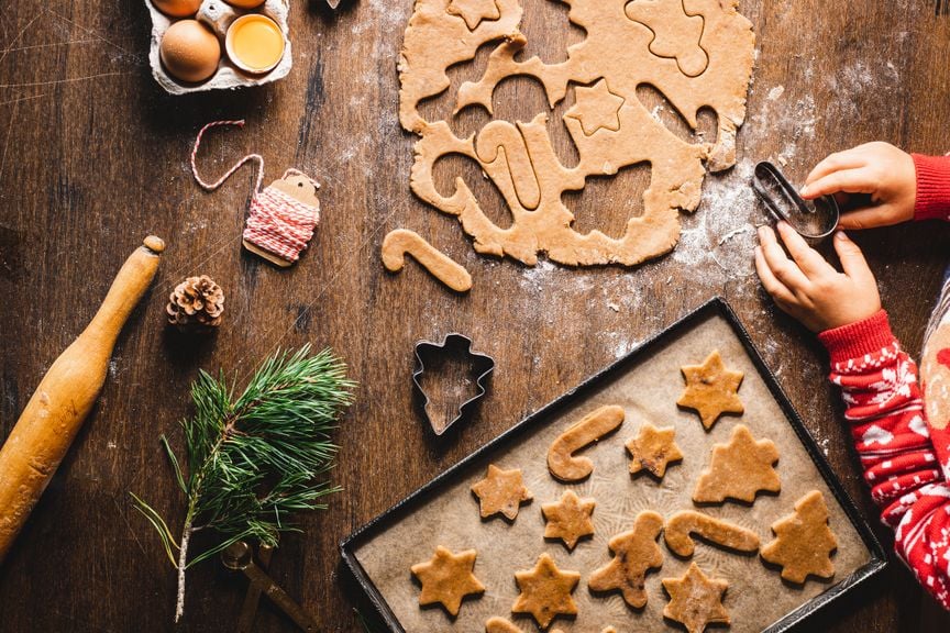 Kind sticht mit Guetzliformen Lebkuchen aus Lebkuchenteig aus