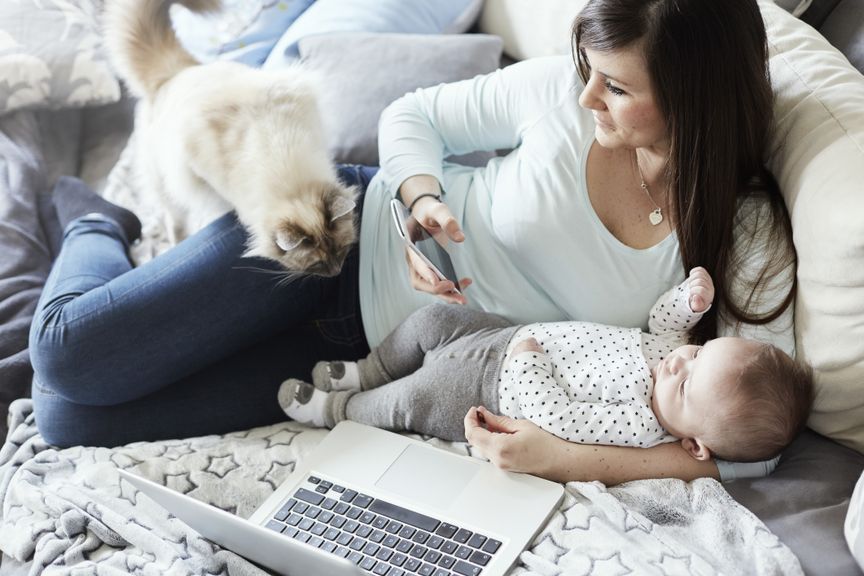 Mutter liegt mit Baby und Katze auf dem Sofa