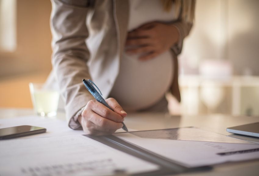 Schwangere Frau unterschreibt ein Dokument 