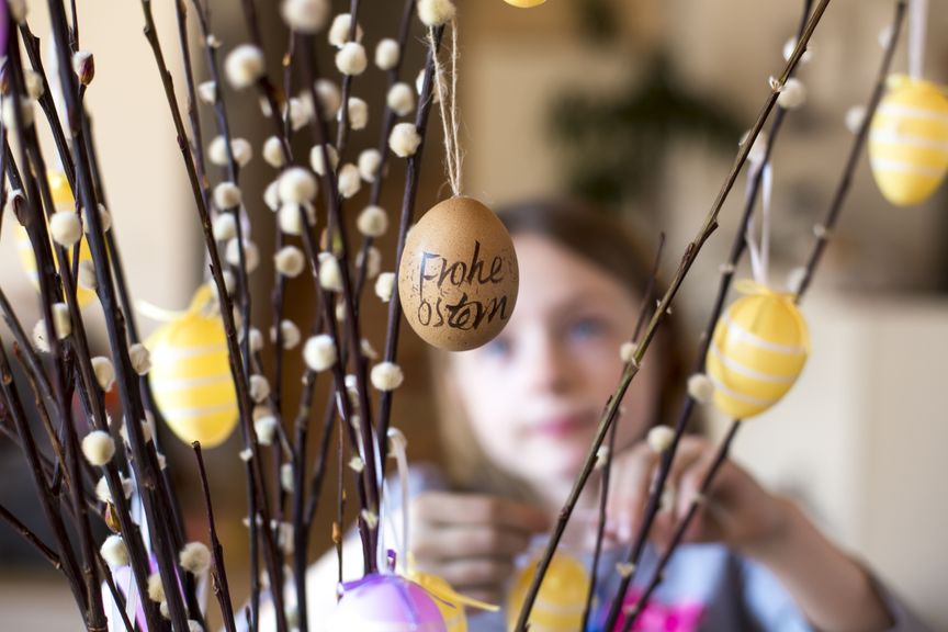 Kind dekoriert Weidenzweige mit Ostereiern