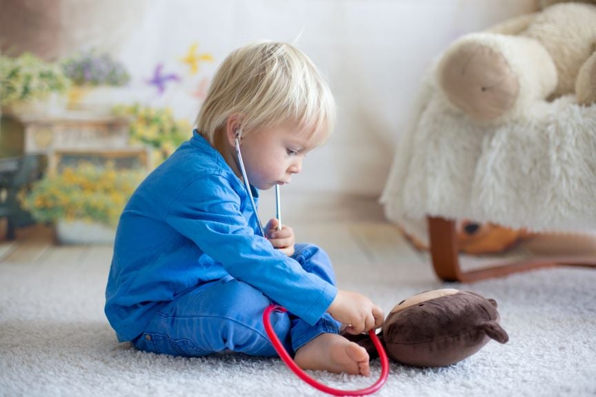 Kleiner Junge hört mit Stethoskop sein Kuscheltier ab