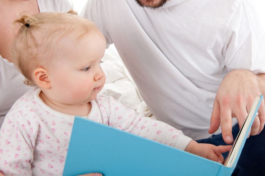 Baby schaut sich mit den Eltern ein Bilderbuch an