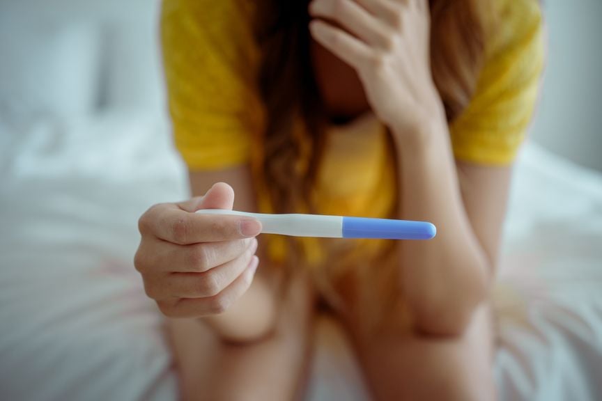 Junge Frau hält Schwangerschaftstest in der Hand