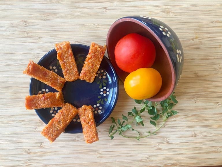 Mini-Polentaschnitten auf blauem Teller mit Tomaten und Oregano