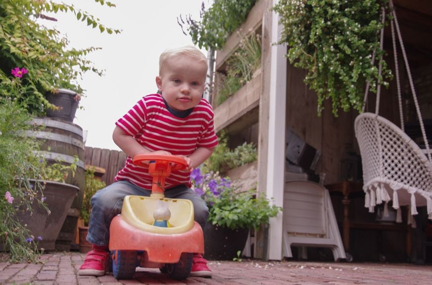 Kind mit Rutschauto im Garten