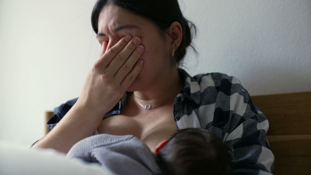 Müde Mutter stillt ihr Baby