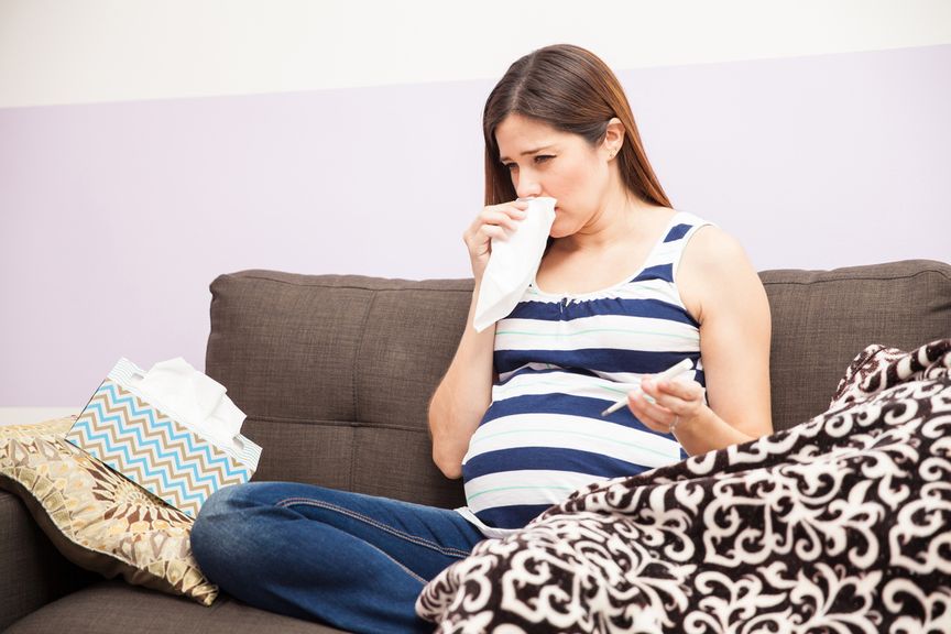 Schwangere mit Fieberthermometer und Nastuch