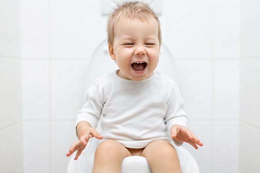 Lachendes Kleinkind sitzt auf der Toilette