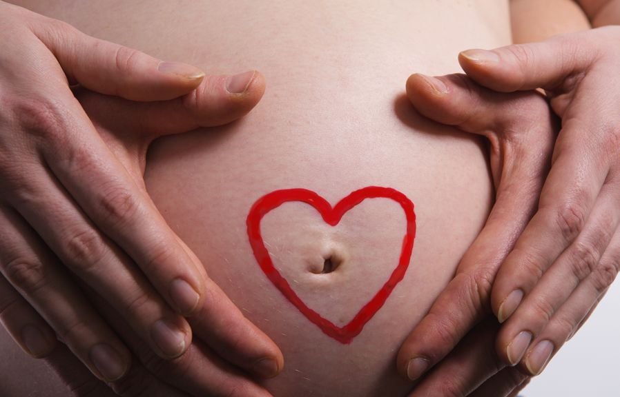 Schwangerschaftsbauch mit Herz und Händen