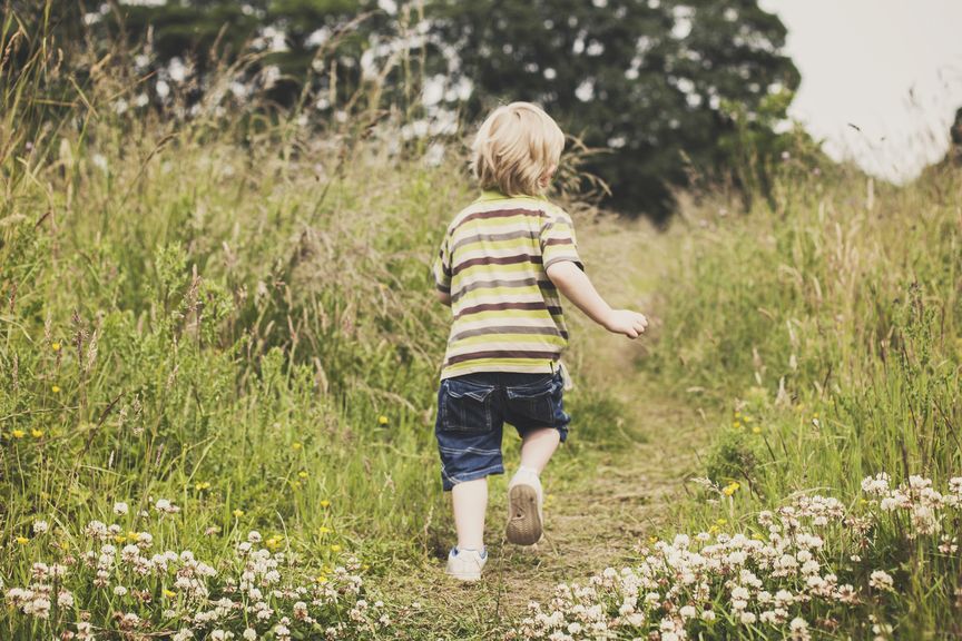 Kind springt auf der Wiese