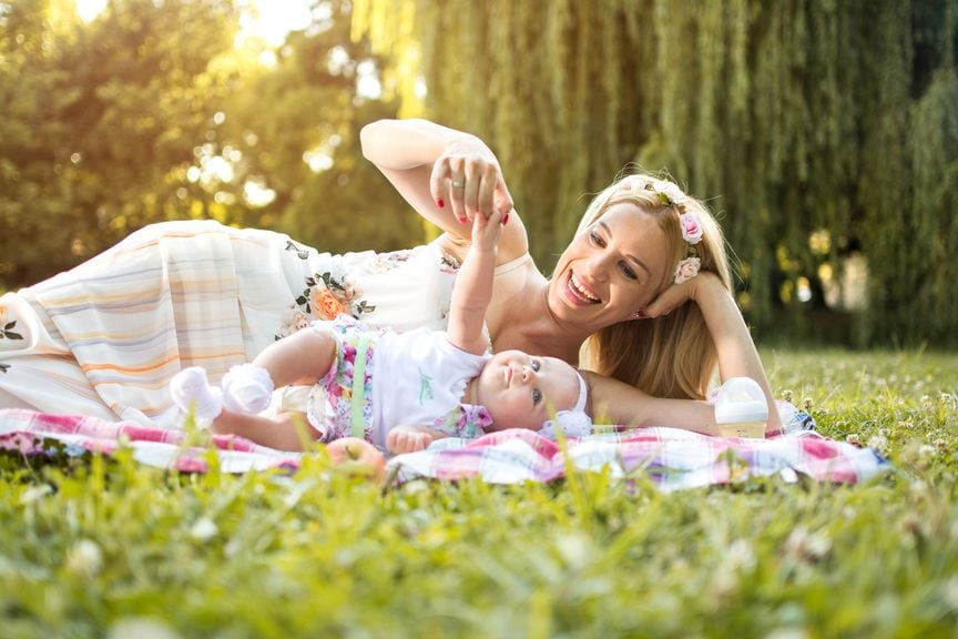 Mama mit Baby liegen im Gras
