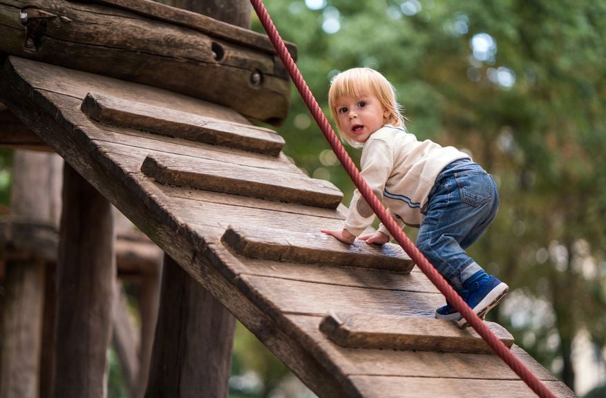 Kind klettert auf dem Spielplatz