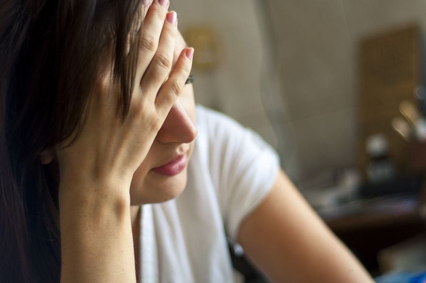 Frau hält sich die Hand an die Stirn