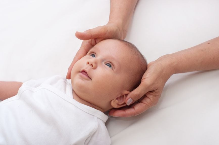 Hände umfassen den Kopf vom Baby