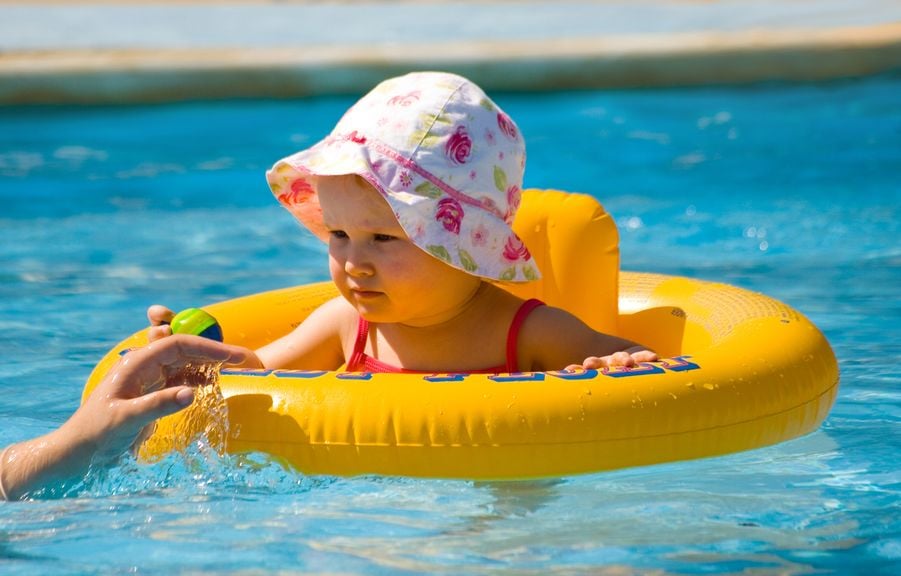 Baby mit Sonnenhut und Schwimmsitz im Schwimmbad