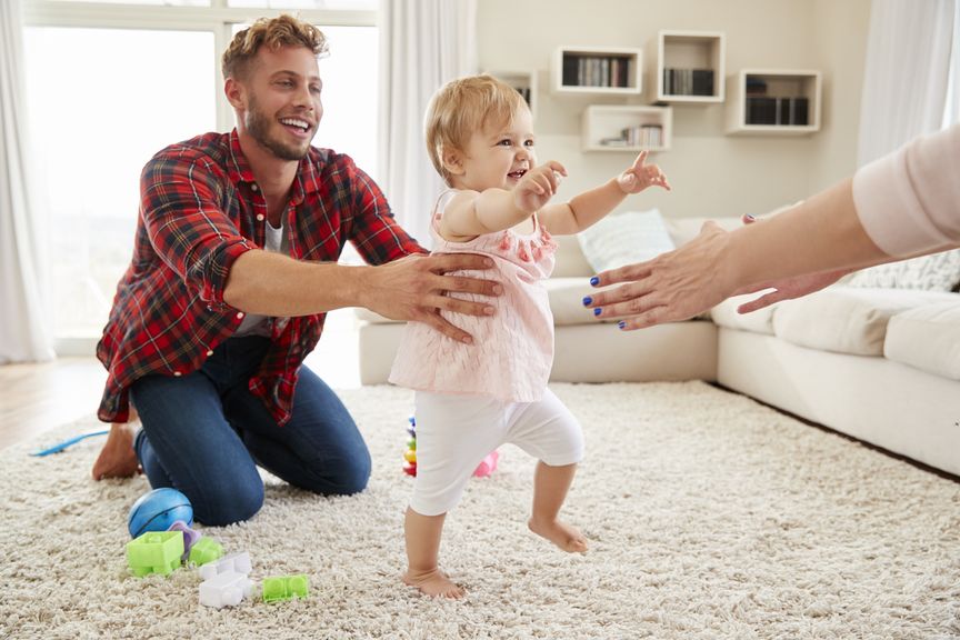 Baby macht erste Schritte zwischen den Eltern