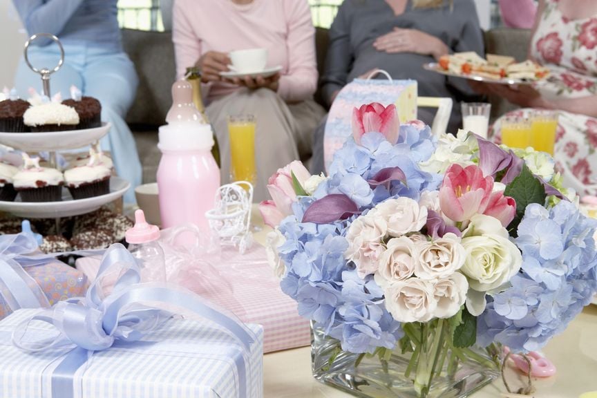 für Babyshower gedeckter Tisch, im Hintergrund die Schwangere