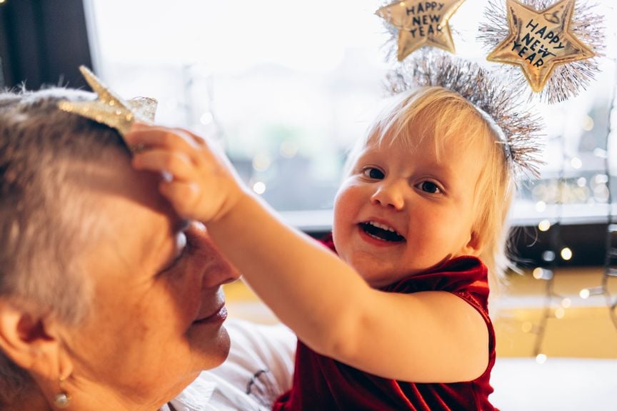 Kleinkind mit Neujahrs-Haarreif feiert mit der Grossmutter Silvester