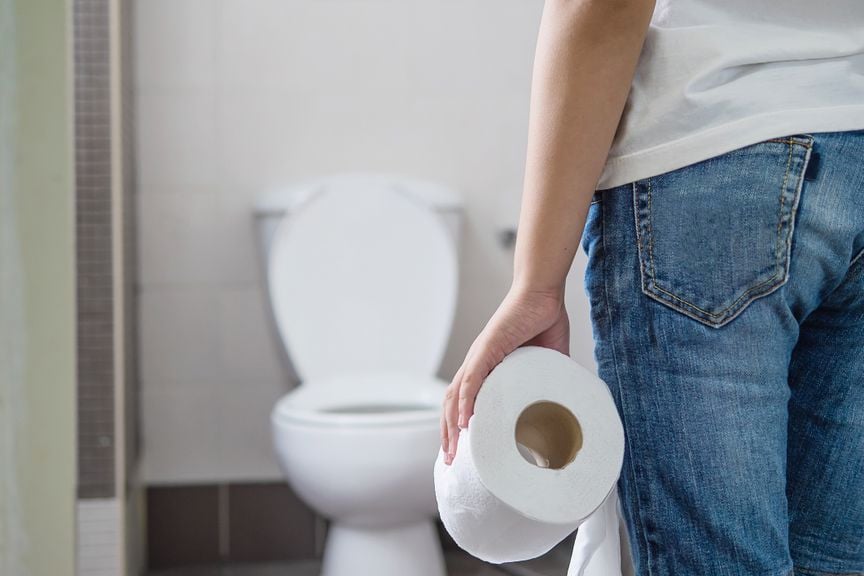 Mit Toilettenpapier in der Hand vor dem WC